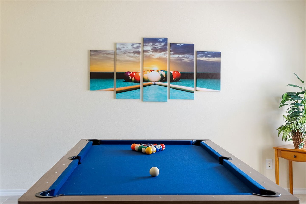 Step into a game room with a sparkling pool table and vivid wall art.