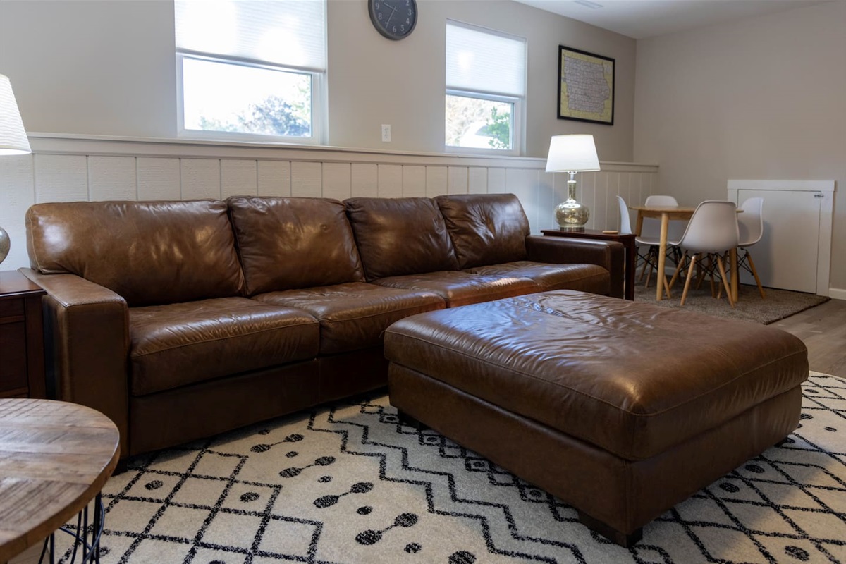 Lower-Level living room. You will find this room comfortable and relaxing. Space complete with a table suitable for games or catching up on work. This space also includes an electronic fireplace and TV to enhance your experience. 