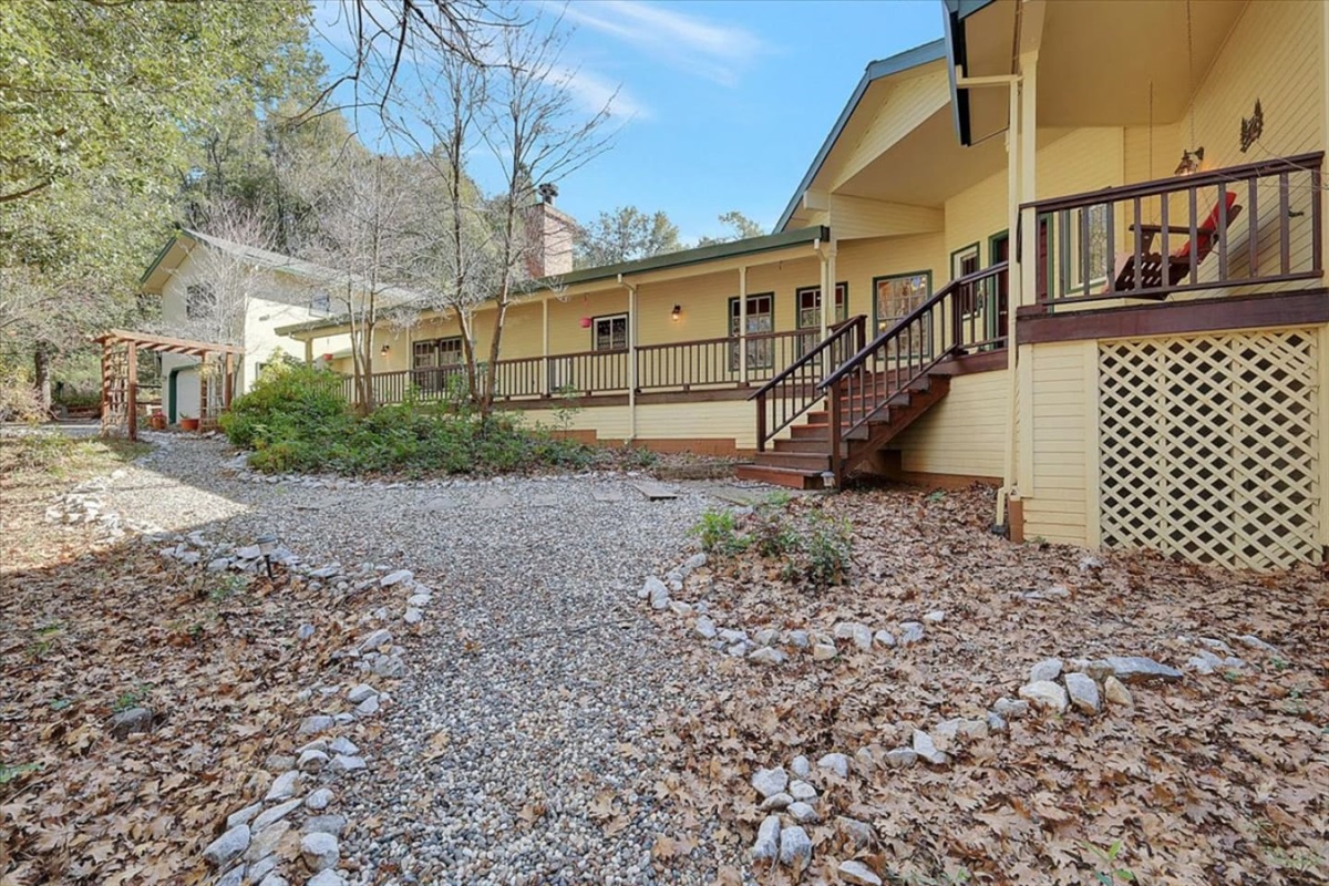 Wooded side yard with a gravel path, trees, and a quiet cabin setting.
