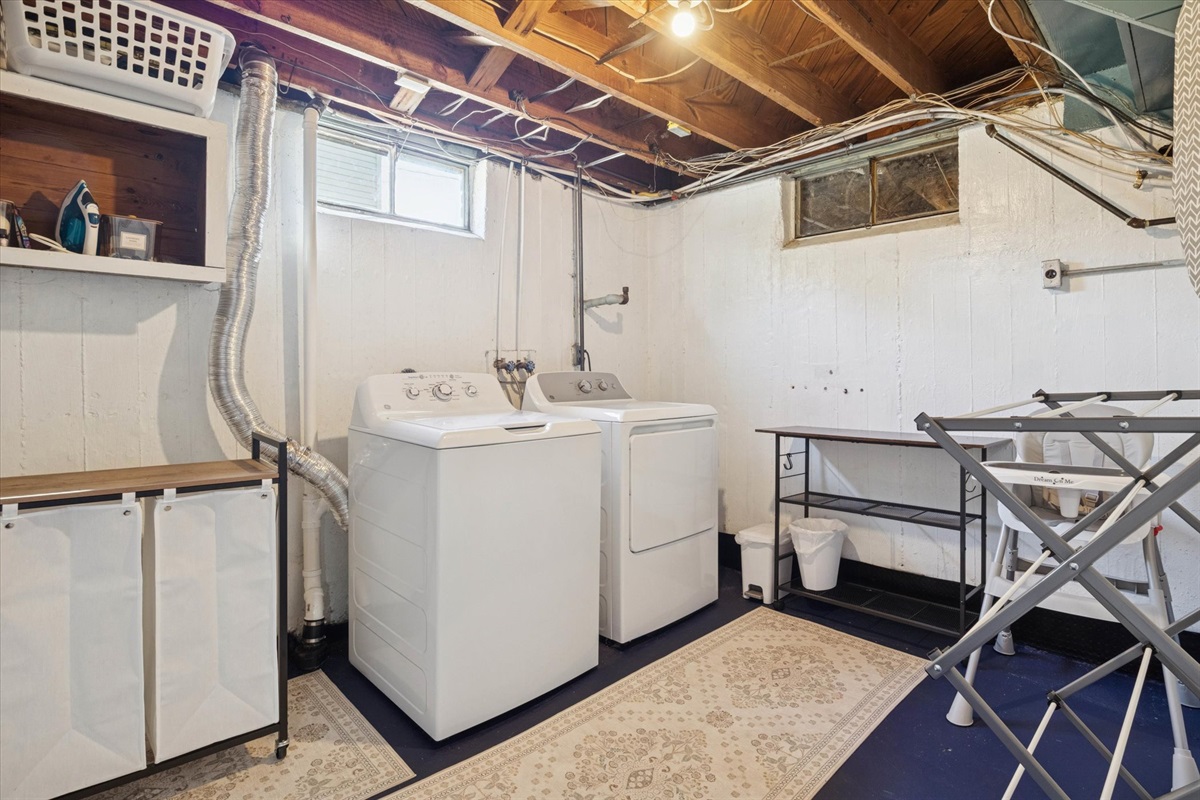 Fresh, functional, and family-ready—our South Bend guest retreat laundry room features oversized machines, drying rack, folding table, baskets, bins, dryer balls, and laundry pods for easy upkeep.