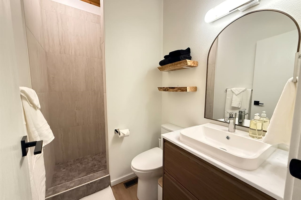 Mountain-lodge shower - tile shower with river rock base, vanity with deep drawers for bathroom items, live edge shelves for convenience and comfort height for those sore quads. 