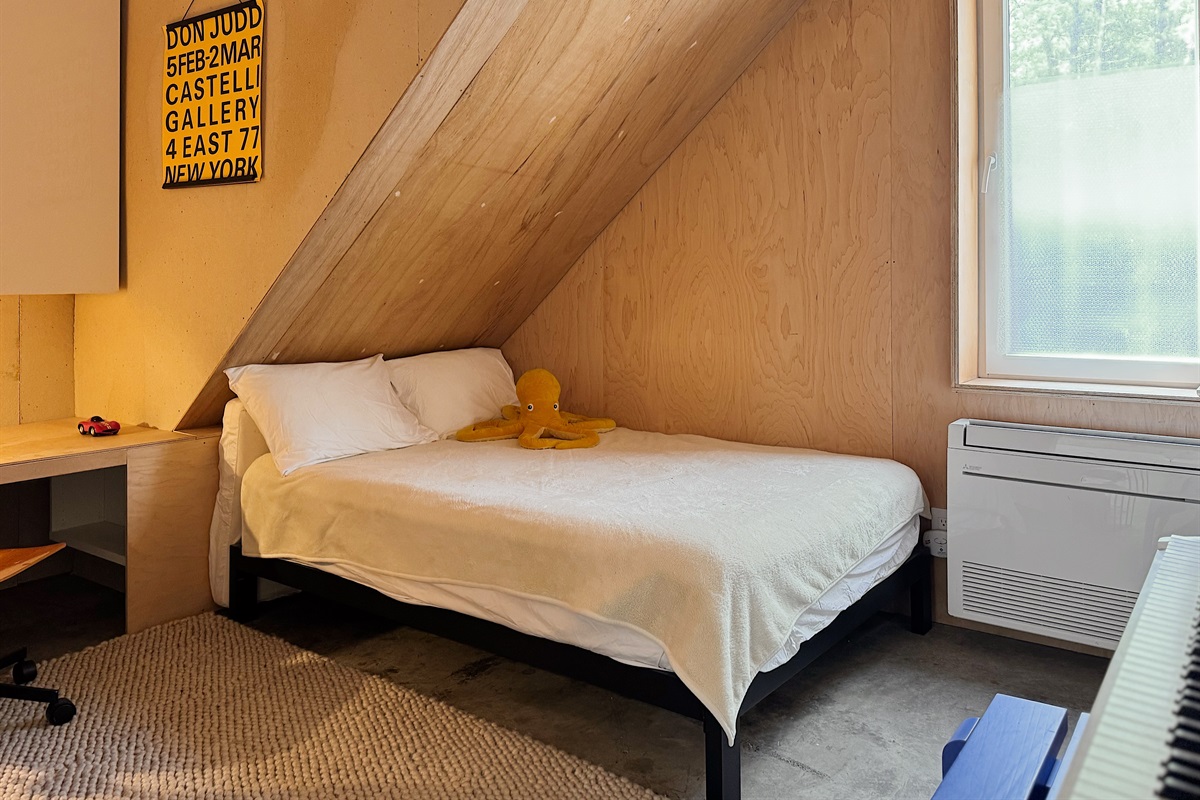 Smaller downstairs bedroom with digital piano, kid-height desk, and kids books.