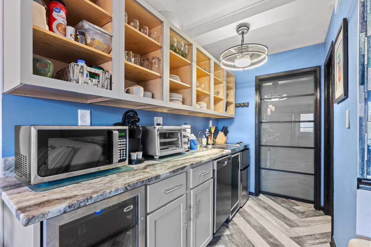 Well stocked kitchen with mini-fridge, microwave, dishwasher, and beverage fridge.