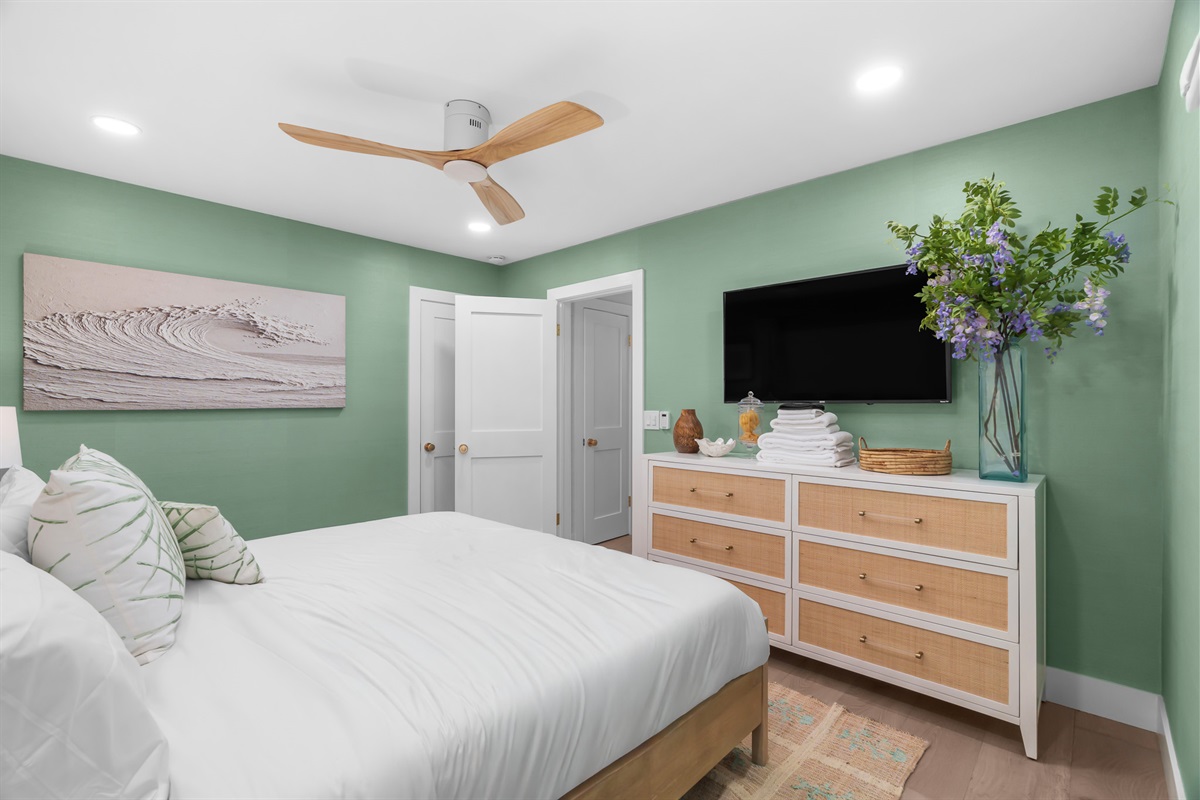 Retreat to the primary suite, featuring soothing sage tones and a large flat-screen for cozy movie nights.