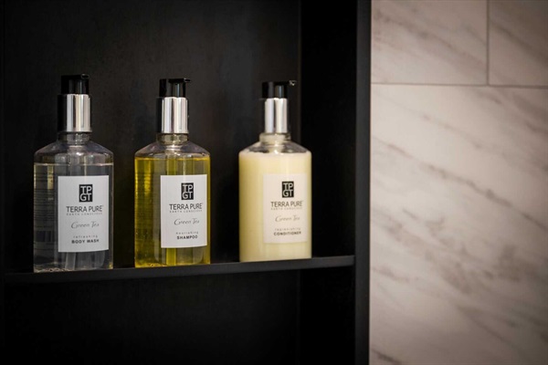 Guest bathroom shower niche with provided shower gel, shampoo, and conditioner. 