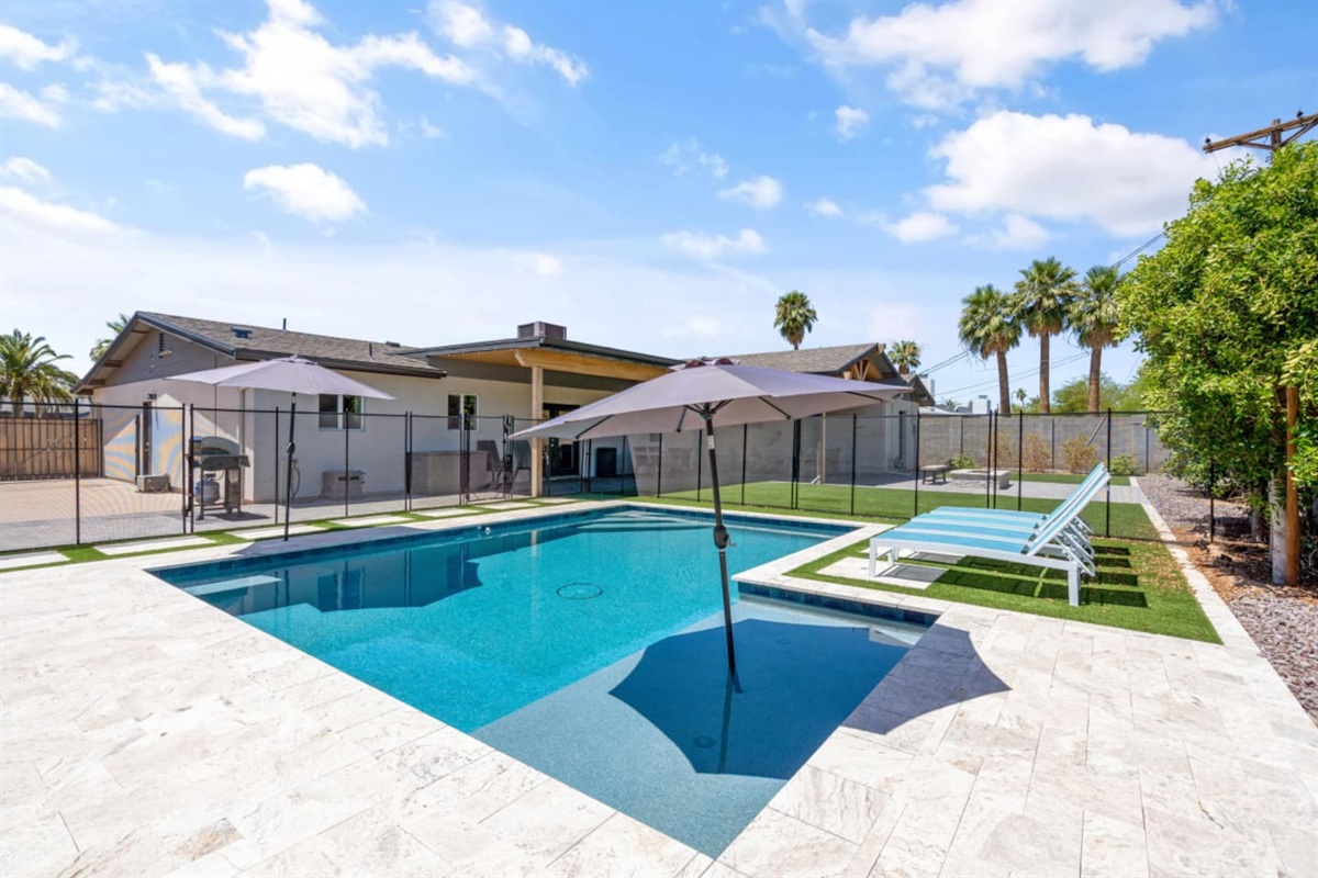 Private backyard pool with lounge chairs, umbrella shade, fire pit seating, and a bright outdoor space 