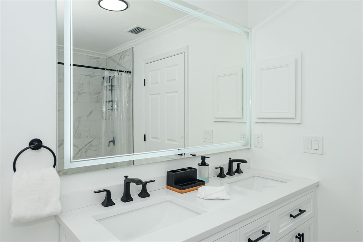 Spacious all-white and black interior bathroom with a stylish sink, combining modern elegance and functionality.