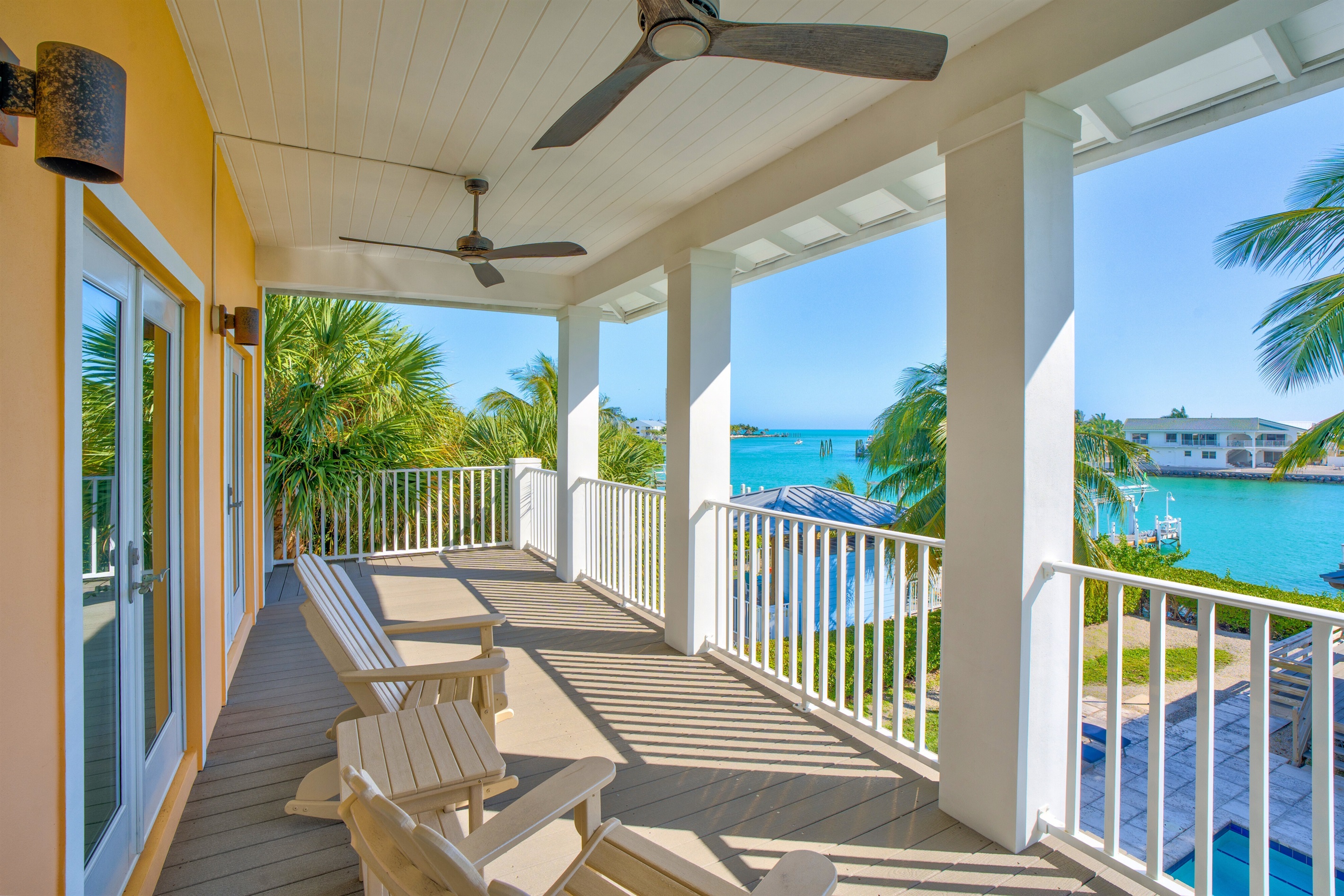 Heading out to the porch off the primary bedroom you have incredible open water views, framed with tropical palm trees.