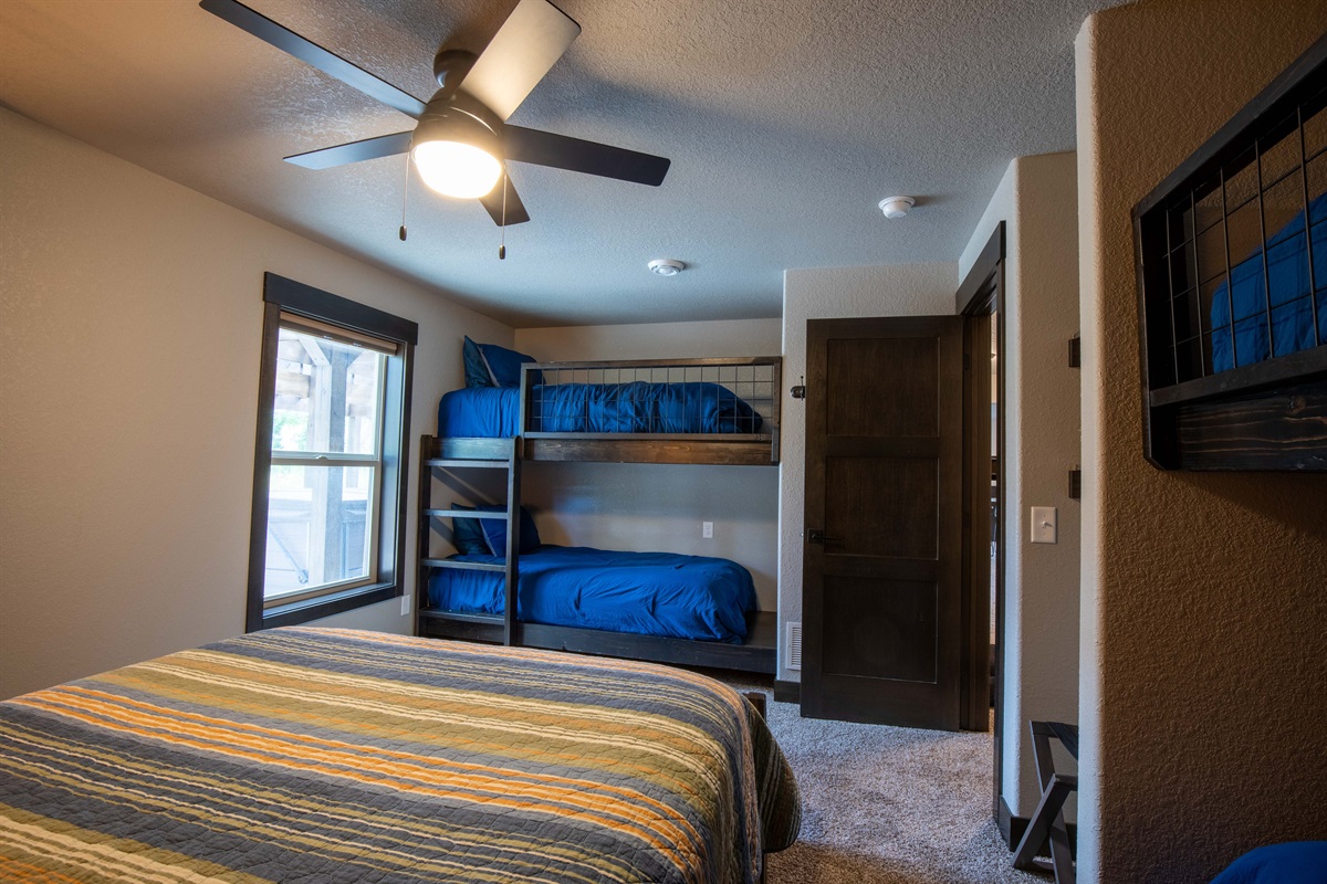 This lower-level room sleeps up to six with a queen bed and 2 sets of twin bunks—perfect for families, cousins, or a fun sleepover-style setup for the kids.