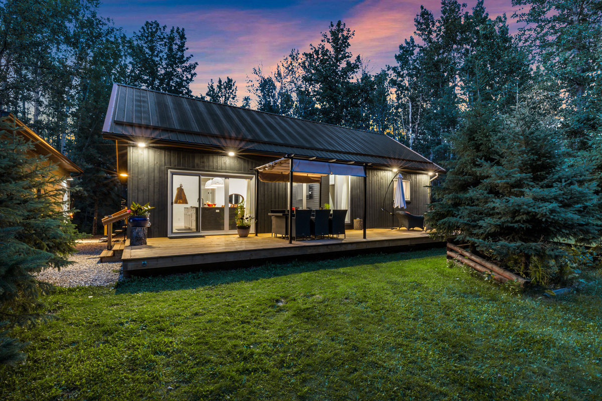 Welcome to Aspen Acre, a peaceful forest cabin where warm evening lights and a spacious deck set the tone for a relaxing getaway.