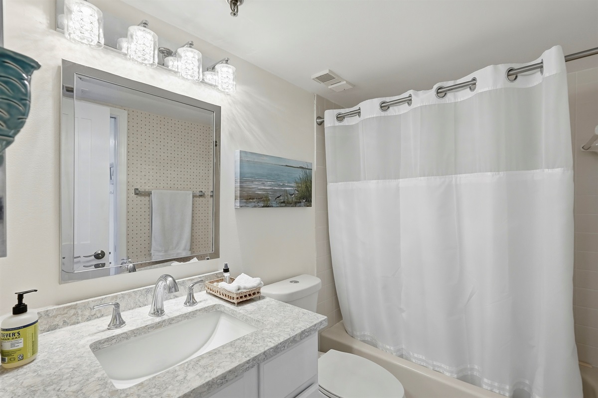 The en-suite master bathroom features a spacious, clean layout with modern finishes, including a vanity mirror, bathtub, shower, fresh towels, and thoughtful details designed for comfort and convenience.
