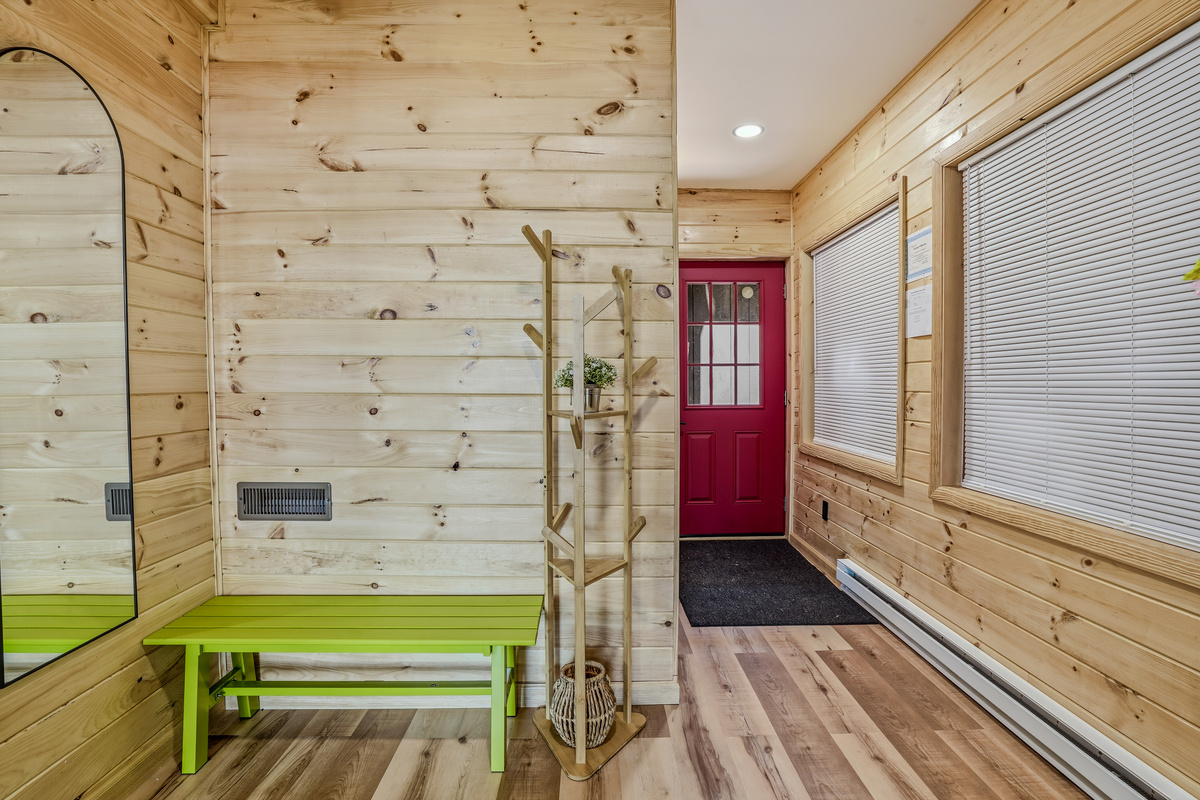 Lower-level front entry — red door, smart lock, mudroom bench, and green accent wall