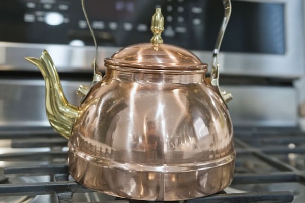 Classic copper tea kettle on the gas stove—perfect for preparing tea, coffee, or hot drinks during your stay.