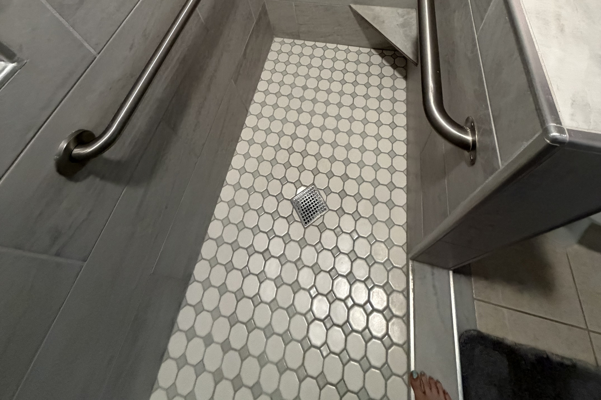 This photo provides a view looking from the front of the shower. Highlighting the layout and accessibility of the space.