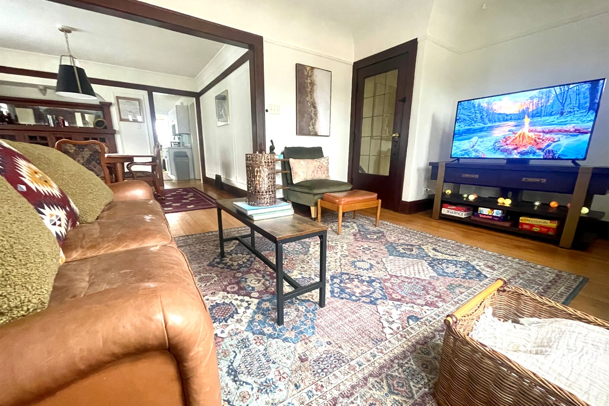 Cozy living room with Smart TV, original Craftsman details, and warm lounge seating—perfect for relaxed evenings after exploring the city.