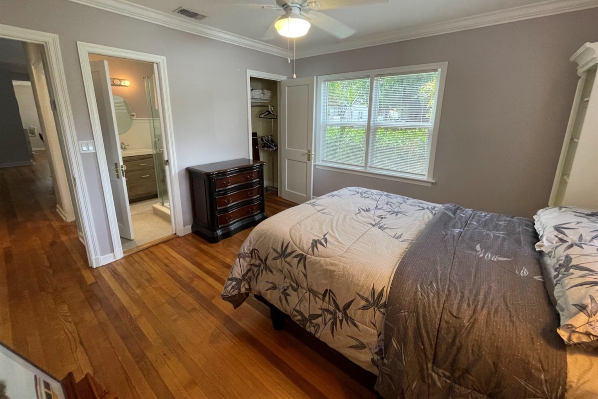 The second bedroom features a queen-zied bed and a stylish painter's floor stand.