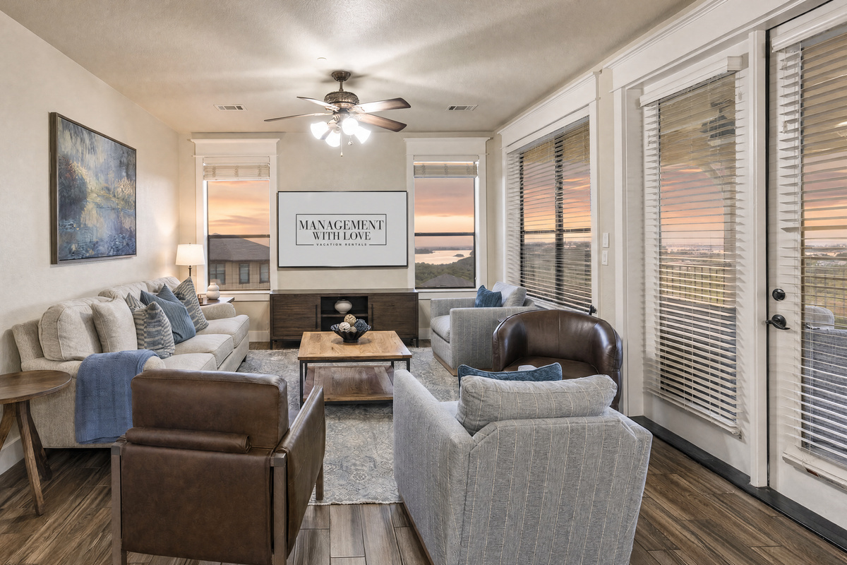 Open living area with comfortable seating, TV, and large windows overlooking Lake Travis. The living room opens directly to the covered balcony.