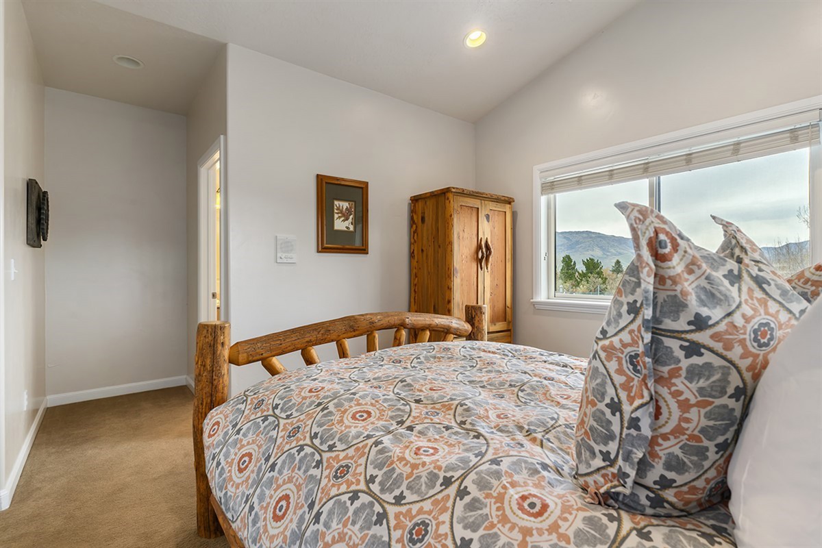 An upper-level bedroom with a queen bed and natural light, creating a peaceful and elevated space to recharge with scenic mountain views.