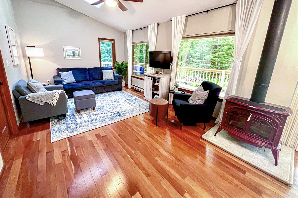 Main Cottage living room open concept two huge panoramic mirror reflective windows wooded views skylight vaulted ceilings tons of natural light 