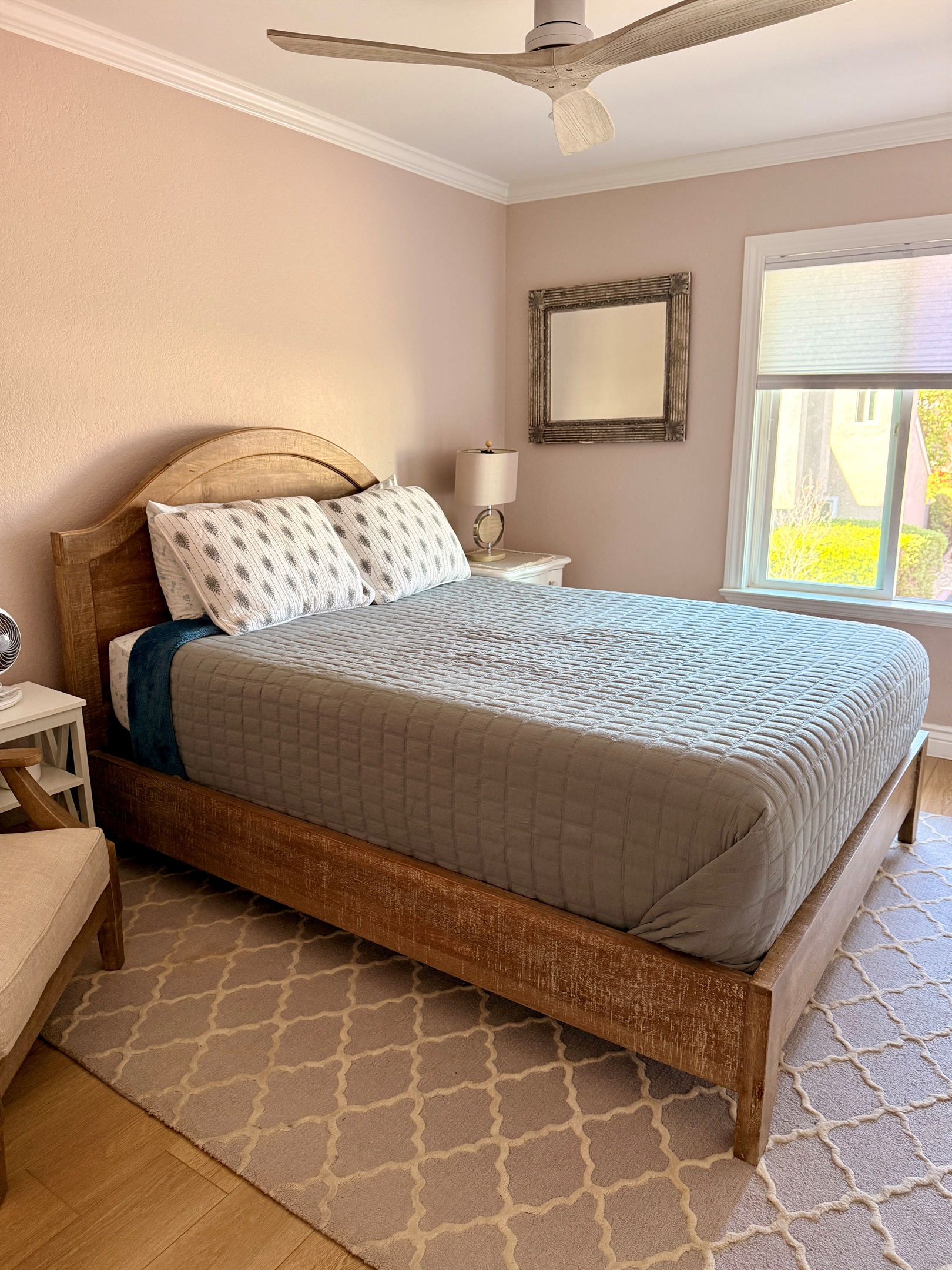 Second bedroom furnished with queen bed and closet with John Louis Home built in organizer and a well-lit reading chair.