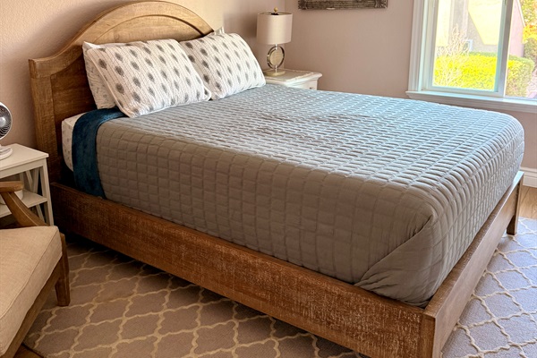 Second bedroom furnished with queen bed and closet with John Louis Home built in organizer and a well-lit reading chair.