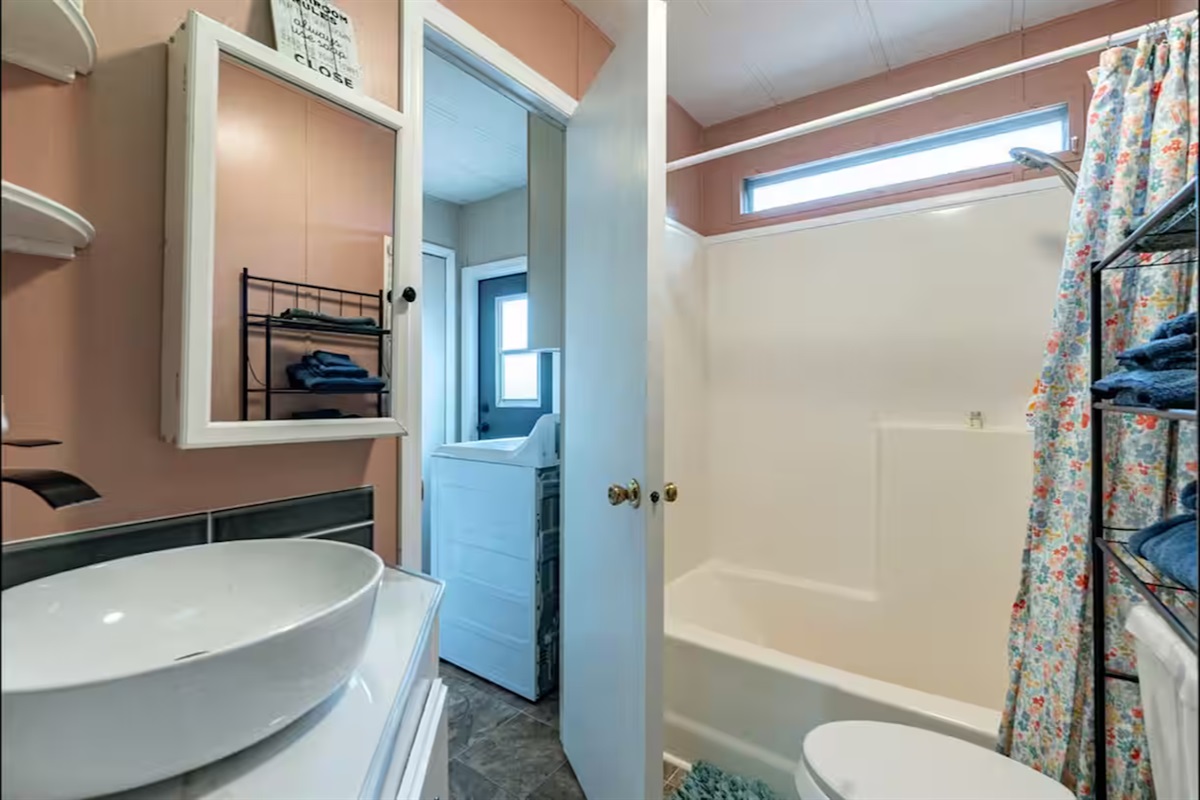 Cozy second full bath with tub-shower combo, fresh towels, and nearby laundry.