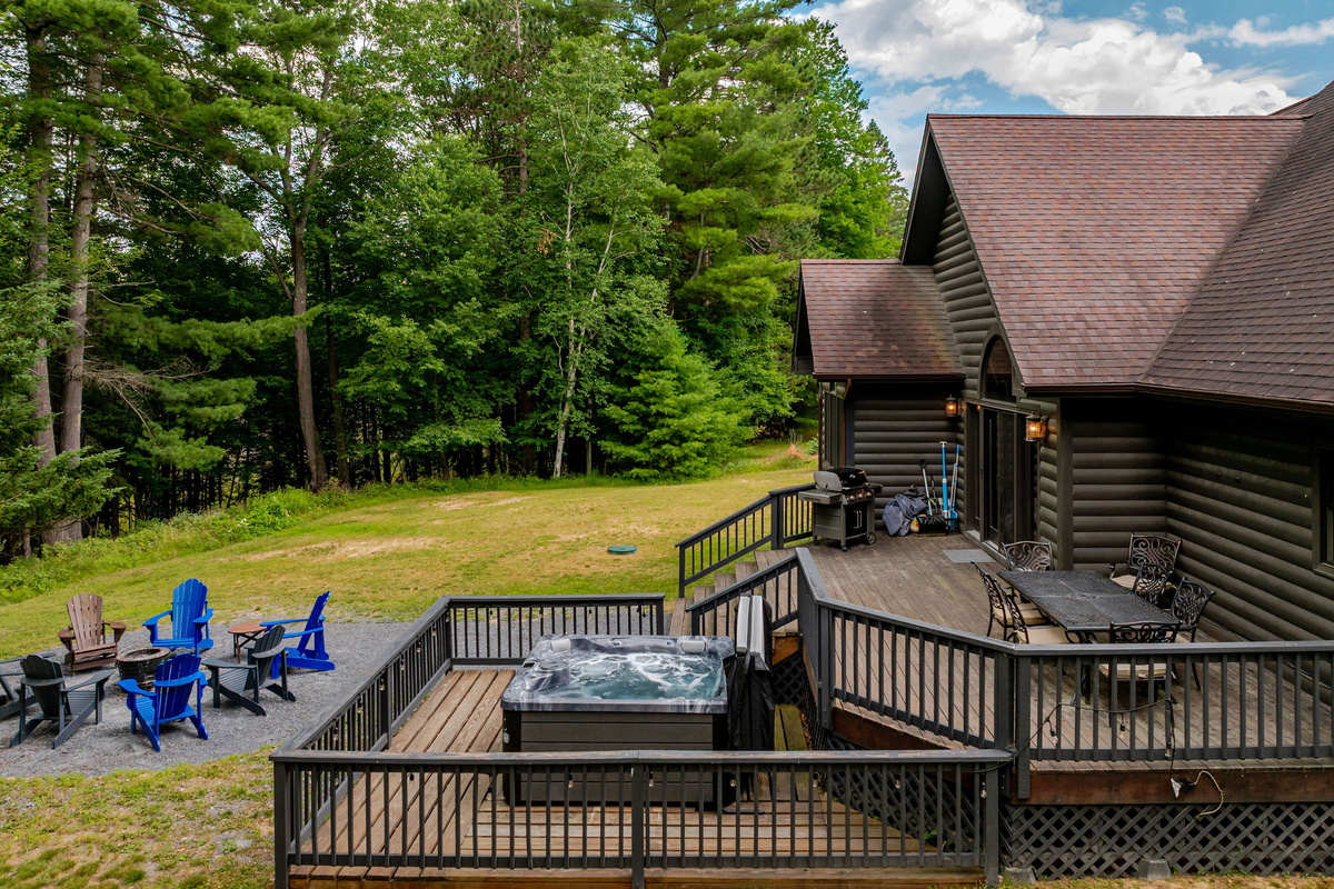 The expansive outdoor living space features a private hot tub, large deck, gas grill, and fire pit—perfect for year-round gatherings.