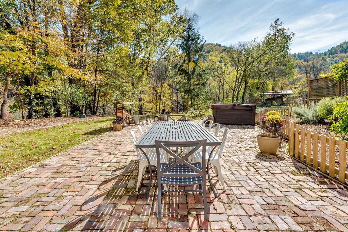 Outdoor dining, grill, firepit, and large hot tub surrounded by gardens