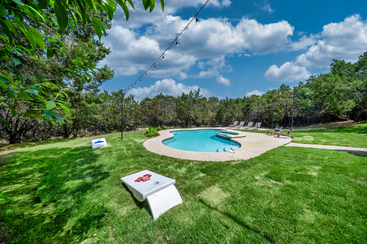 Sprawling green lawn surrounds a sparkling private pool — pure Hill Country charm.