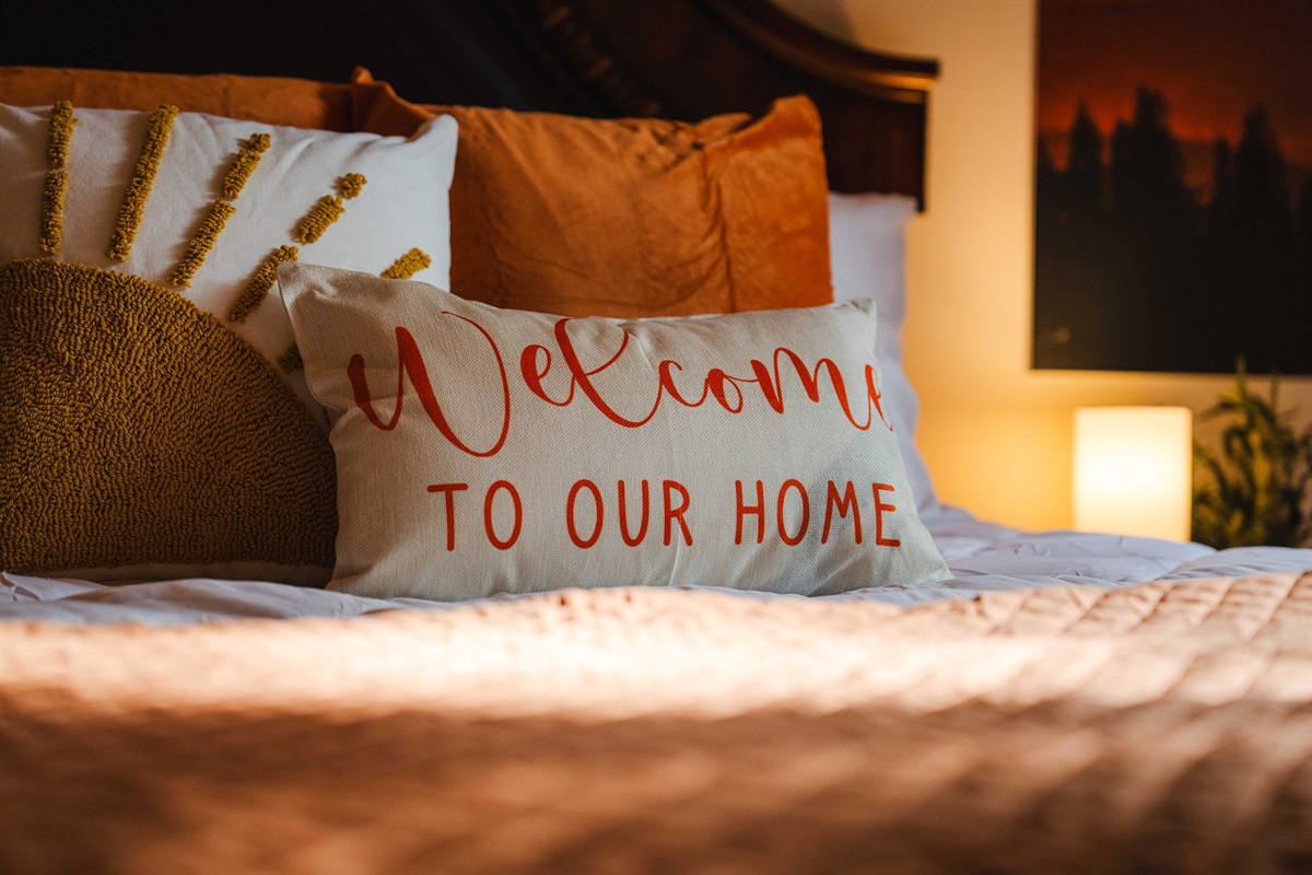 A warm welcome: “Welcome to Our Home” pillow on a perfectly made bed.