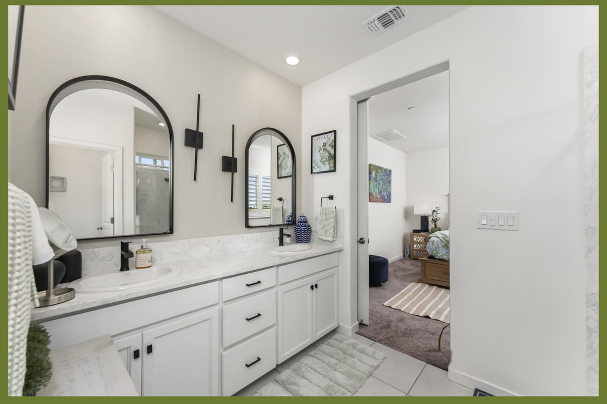 Bathroom vanity with double sinks, arched mirrors, storage drawers, and easy access from the nearby bedroom.