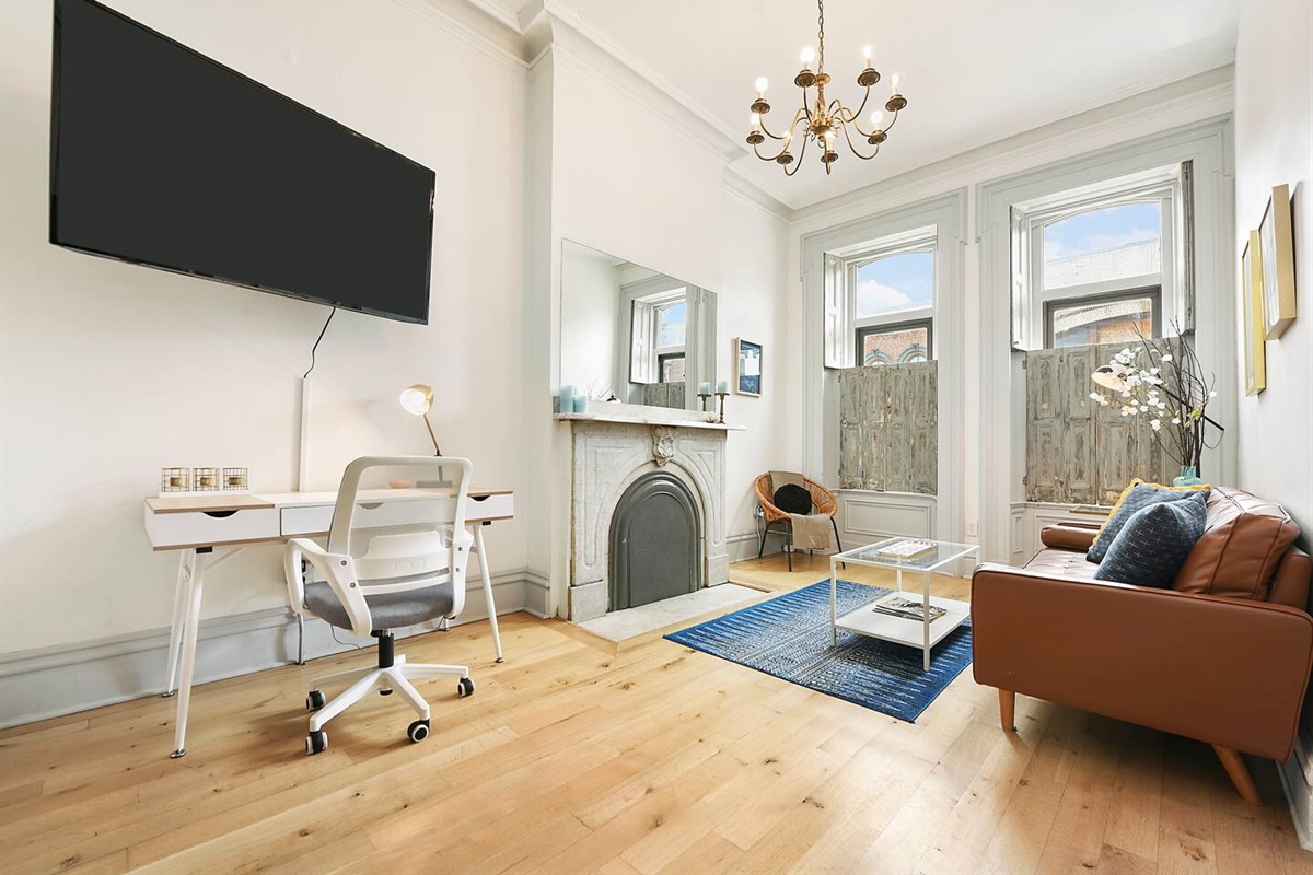Unwind in a cozy living room with a leather couch, extra chair, and coffee table. Enjoy shows on the TV or stay productive at the workstation. A perfect space for relaxation and work, designed for comfort and convenience.