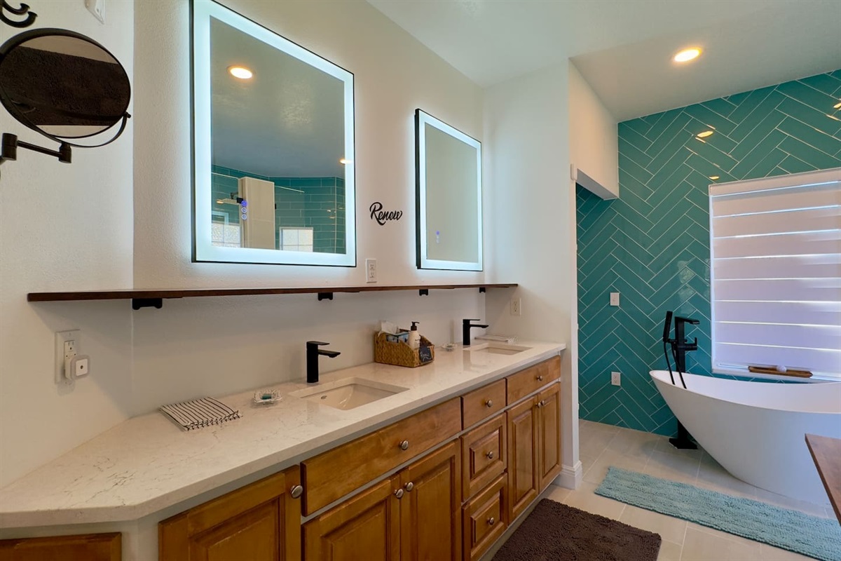 A double-sink setup with white countertop, wooden cabinets, and illuminated mirrors creates a sleek, modern look.