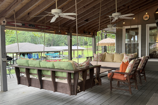 Spacious covered porch with swing beds and lake views — made for relaxing outdoors