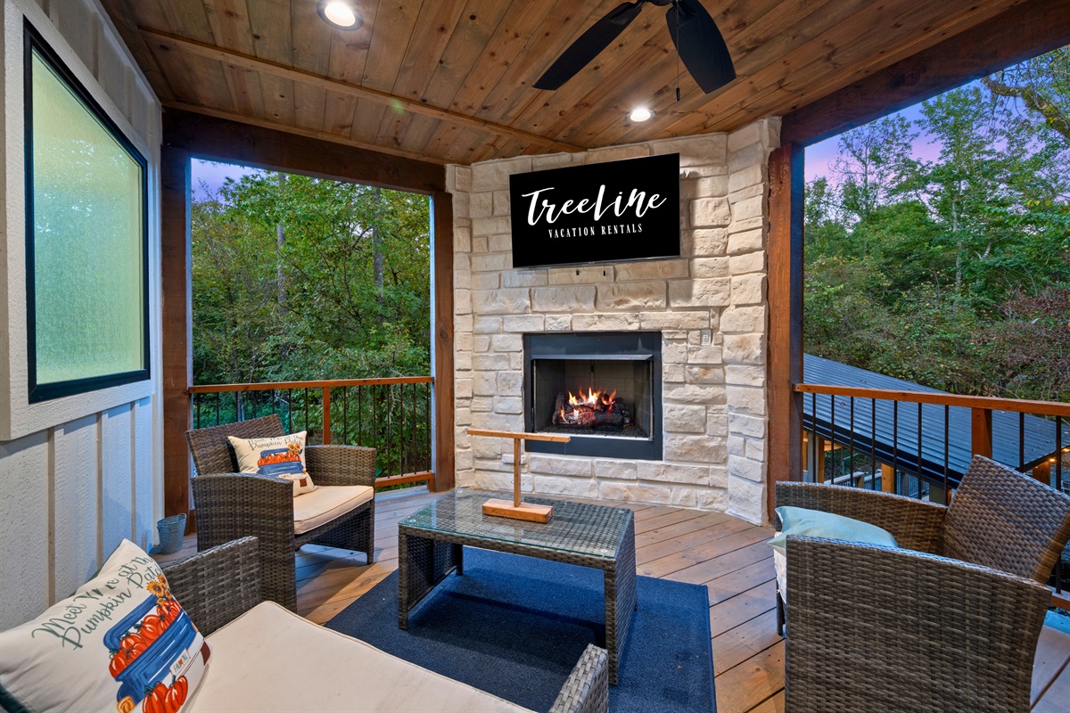 The covered outdoor living area offers a cozy place to relax with comfortable seating and a fireplace that makes the space enjoyable in any season.