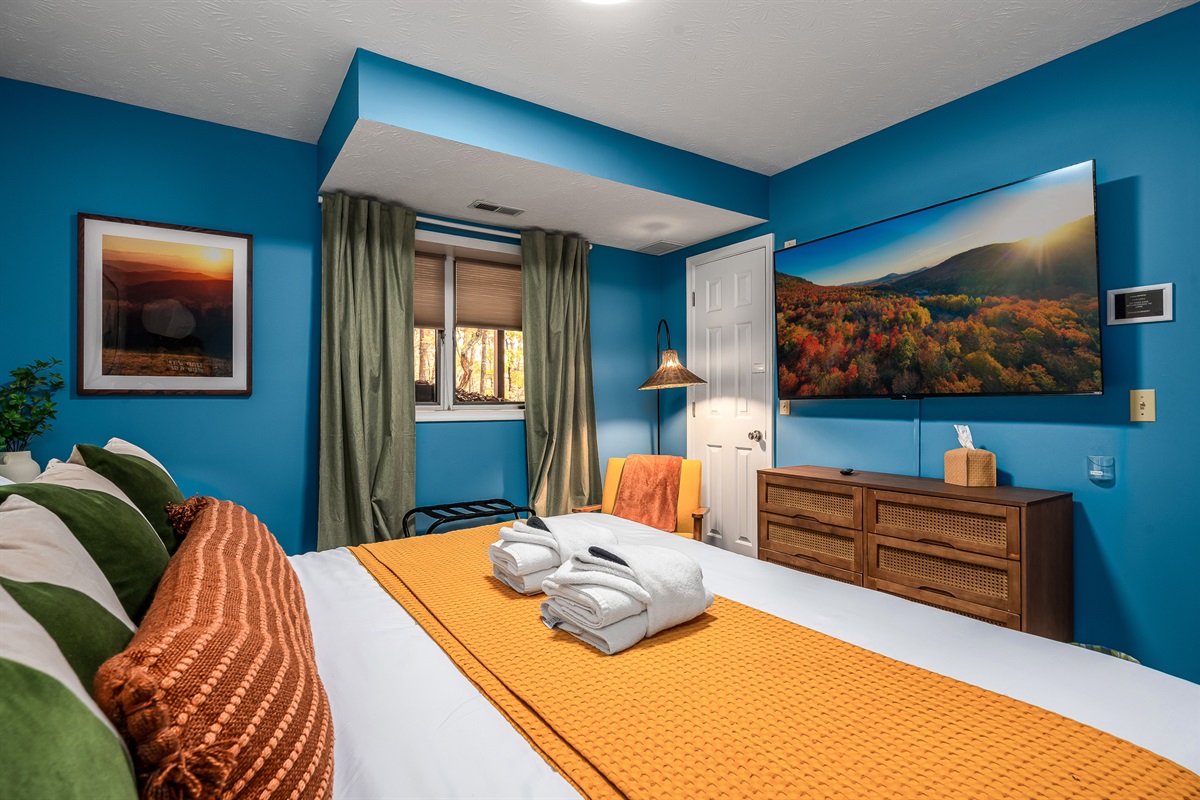 A bright, happy bedroom with forest views and a big-screen TV — perfect for unwinding after a full day outside.