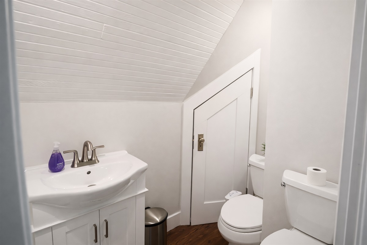 A convenient half-bath tucked away with classic beadboard ceilings and a crisp white vanity.
