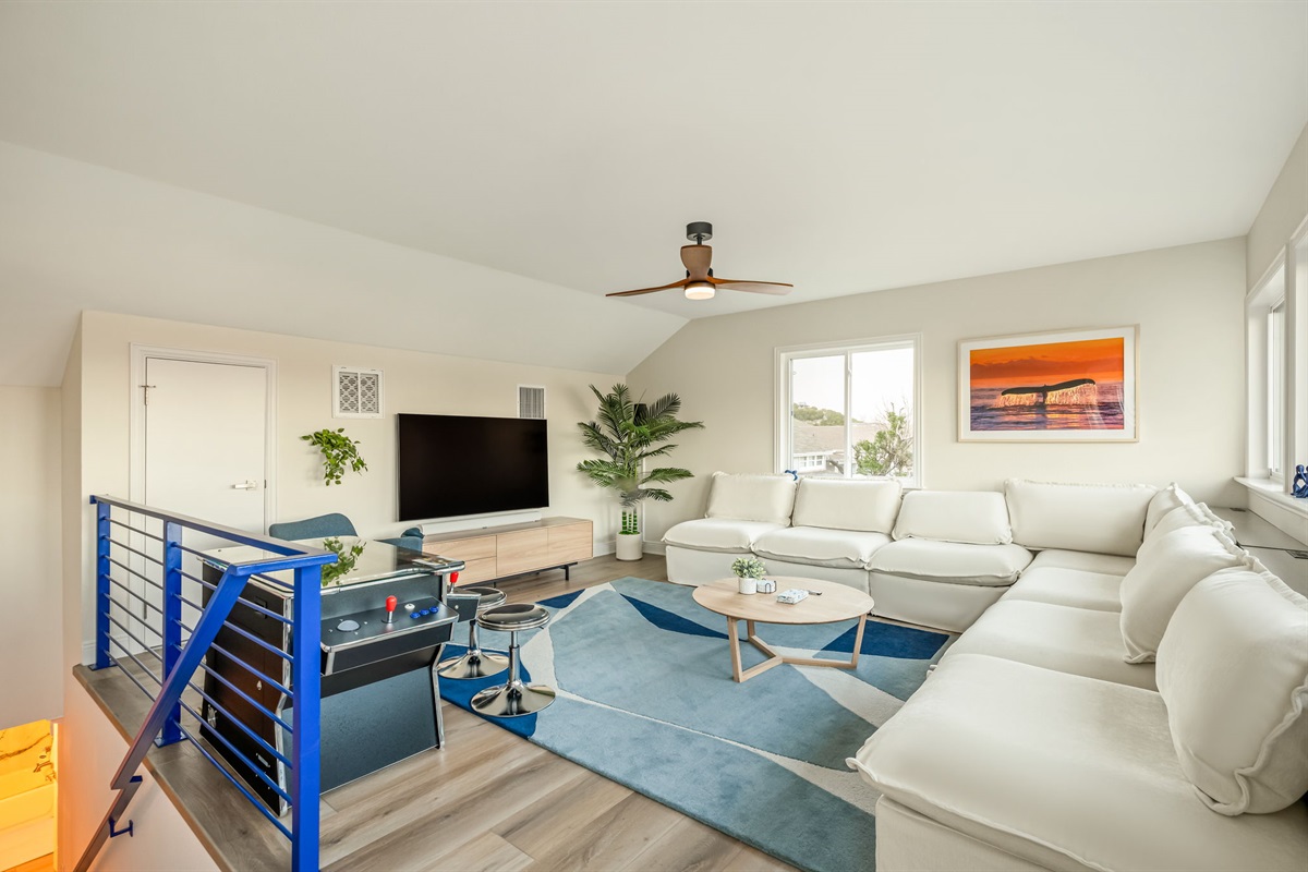 Upstairs living area with wraparound sectional and TV — perfect for movie nights.