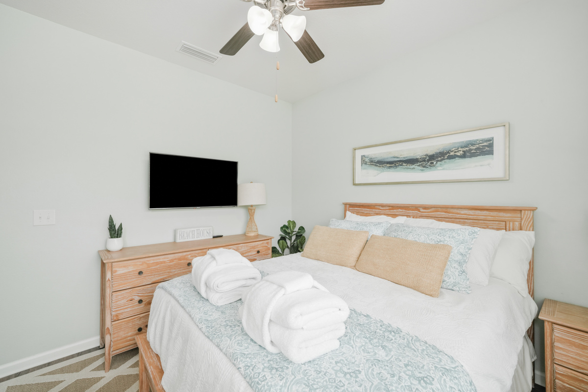 Bedroom 3: Queen bedroom featuring ceiling fan, bedside lamp, plush linens, dresser and Smart TV