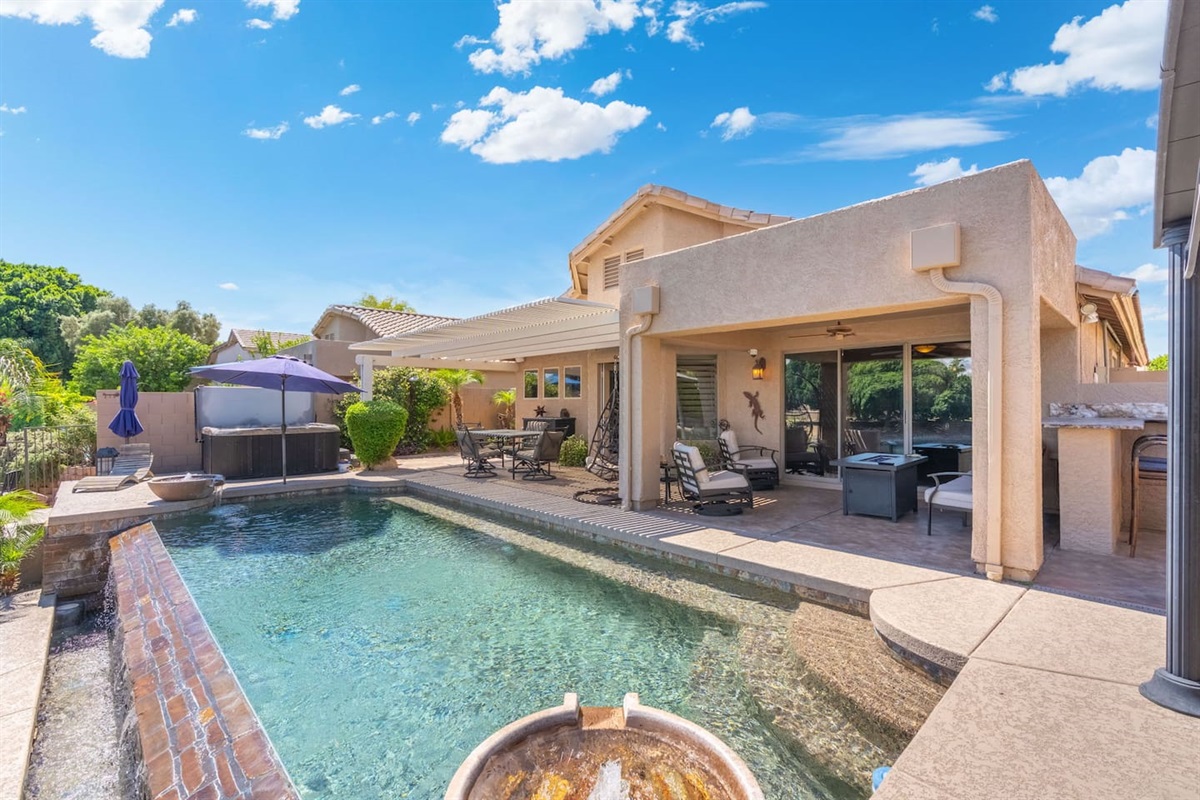 Everything you need for the perfect Arizona day — a sparkling pool, shaded patio with seating, outdoor dining, and the grill ready to go.