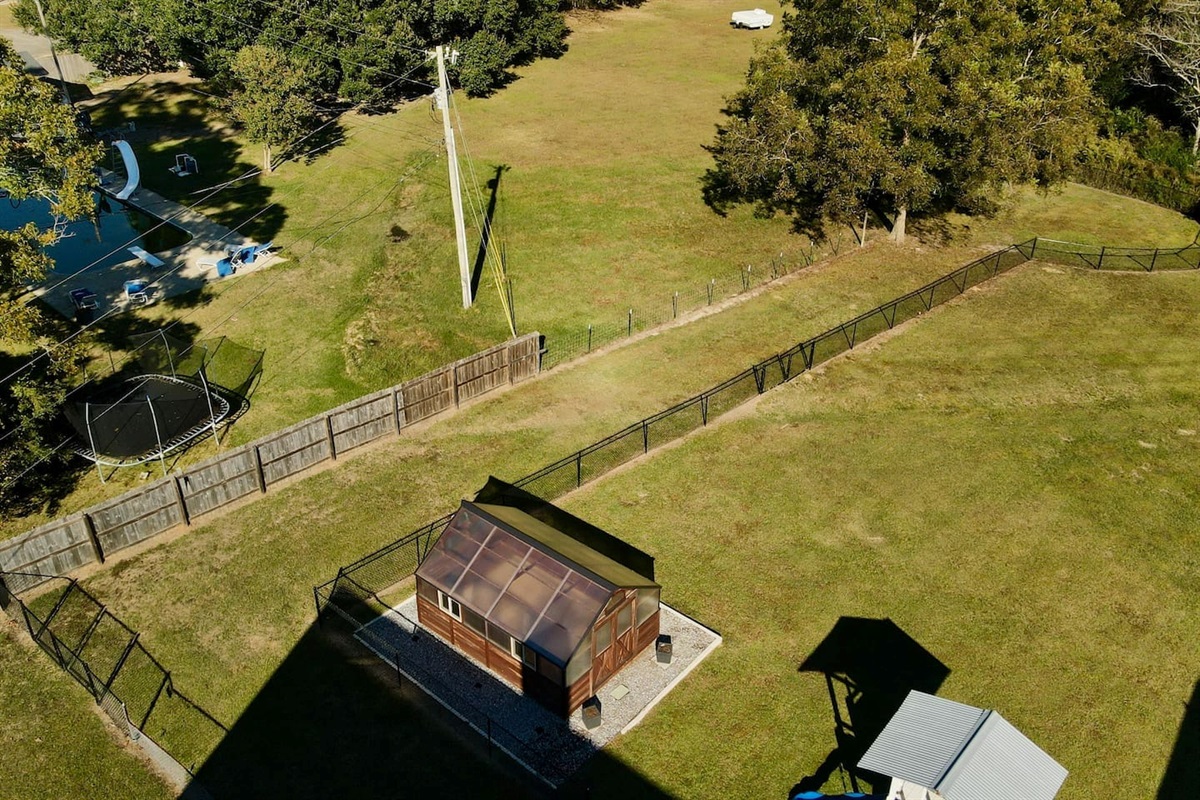 A fenced area with a greenhouse/shed sits alongside wide open grassy fields