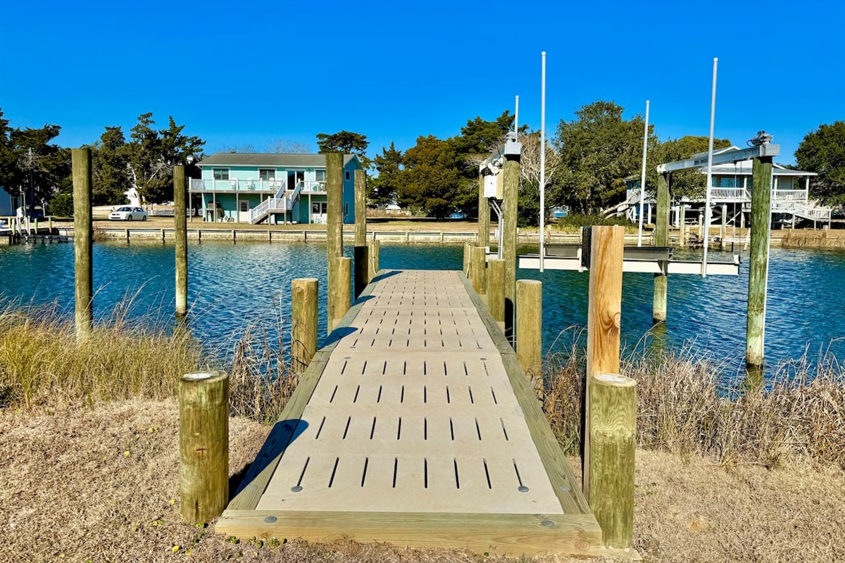 Private backyard dock with boat lift and fillet table, fenced-in backyard, fire pit with Adirondack chairs, hammocks, propane grill, picnic table, outdoor shower, expansive waterfront back deck, neighborhood boat ramp and dock