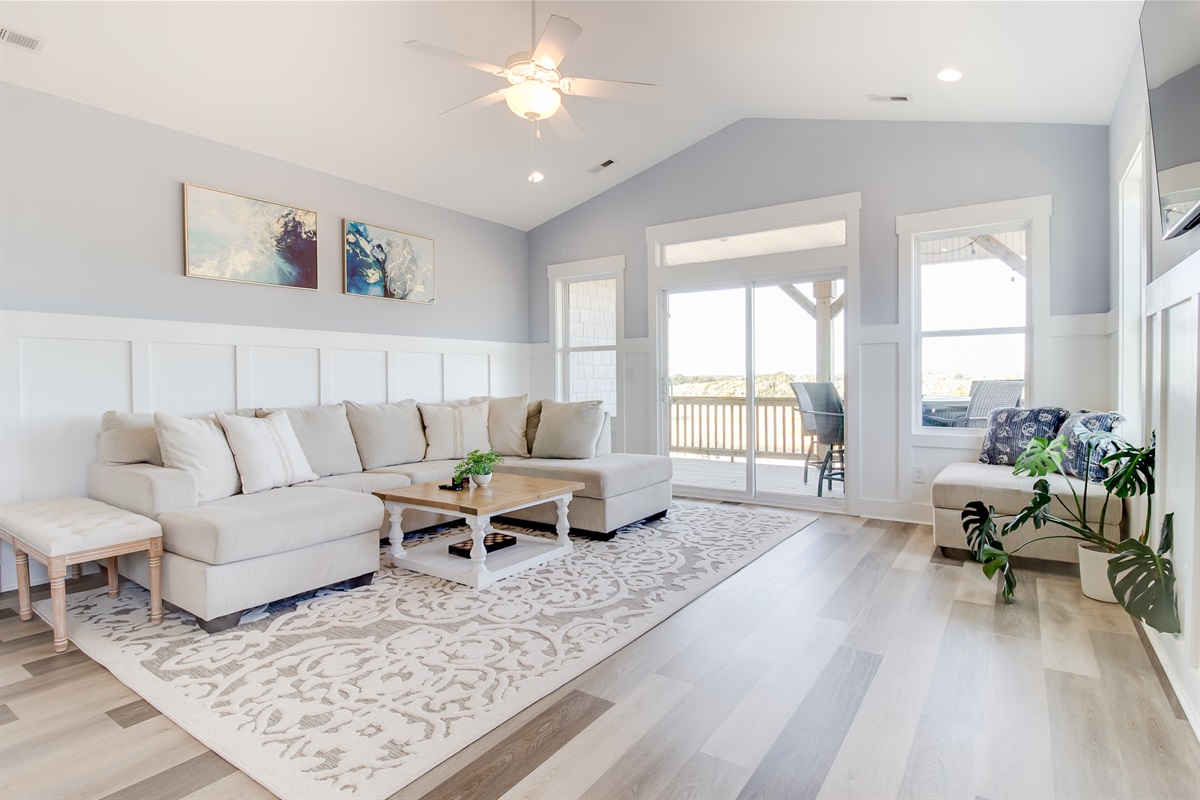 The bright, open living room offers plenty of space to gather, with comfortable seating and direct access to the deck just beyond the sliding doors