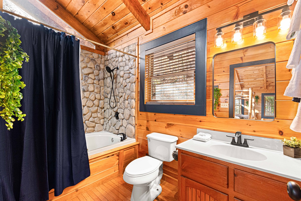 1 of 2 full bathrooms with jacuzzi tub, shower, and grotto style stone walls