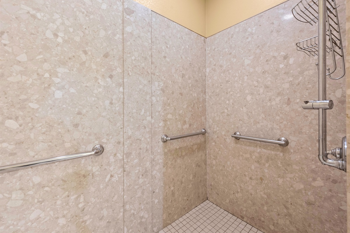 Walk-in tiled shower with grab bars for comfort and safety.