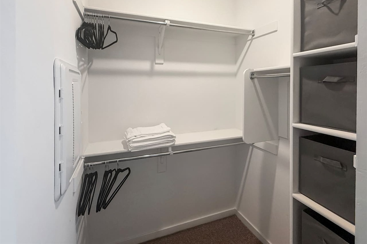 Walk-in closet with shelves, rods, hangers, and folded towels