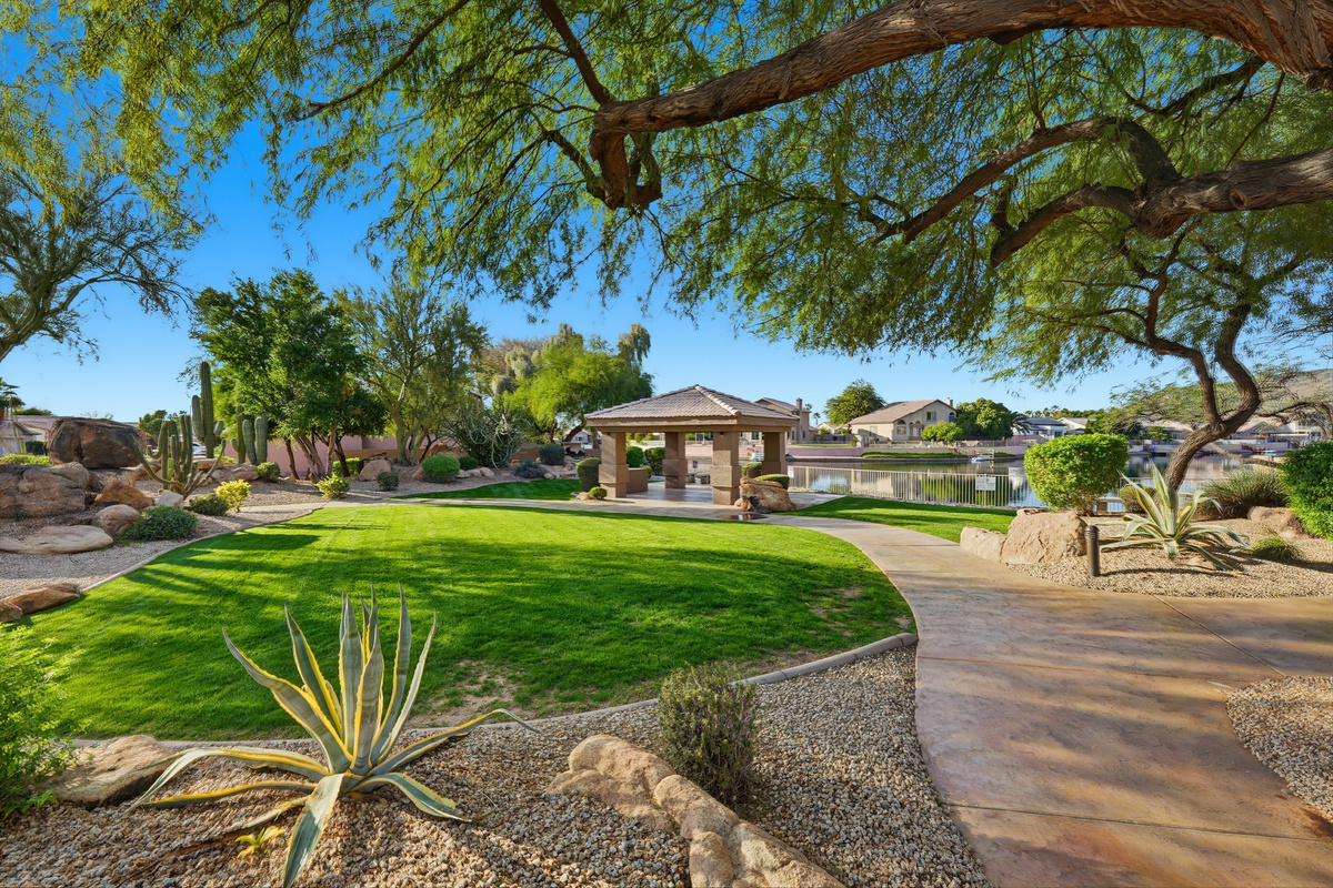 Community lakefront green space with shaded walking paths, desert landscaping, and a peaceful neighborhood setting.