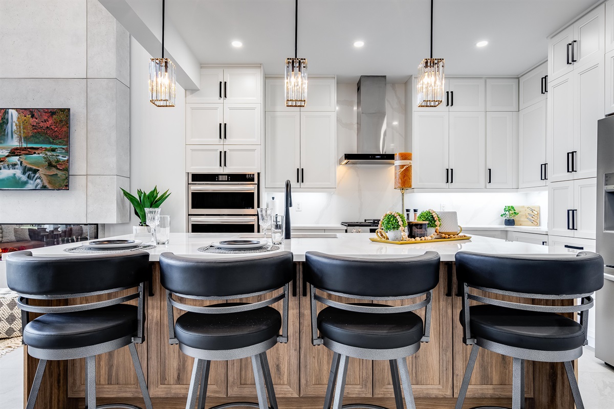 A chef's dream kitchen with extra large eat-in island and high-end appliances including gas stove and two ovens.