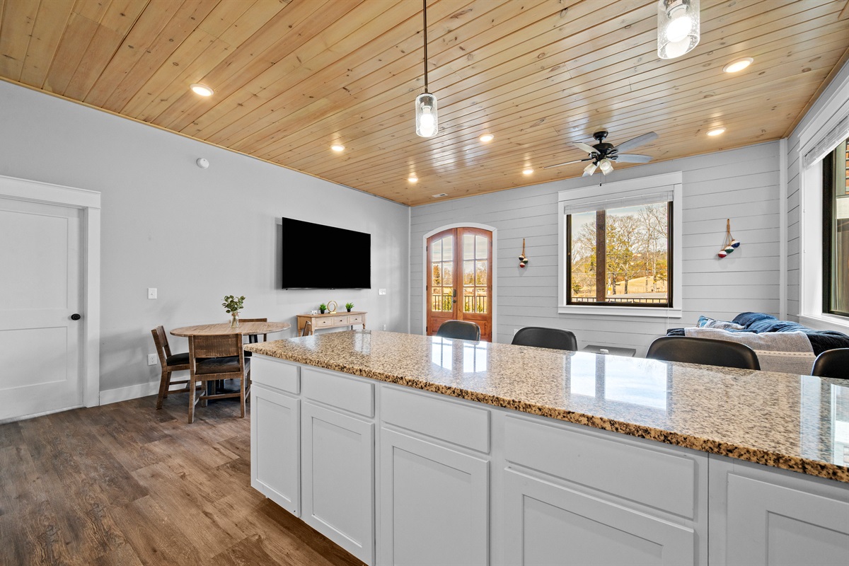 Another view of the open living space with large TV, kitchen, and dining area all in sight—perfect for groups who want both togetherness and comfort.