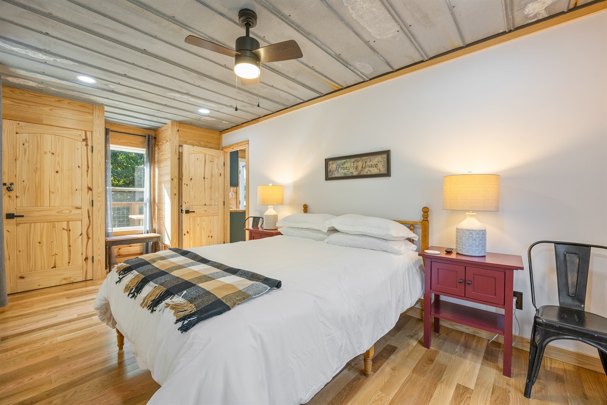 Main level queen bedroom with cozy décor and a peaceful view of the woods.